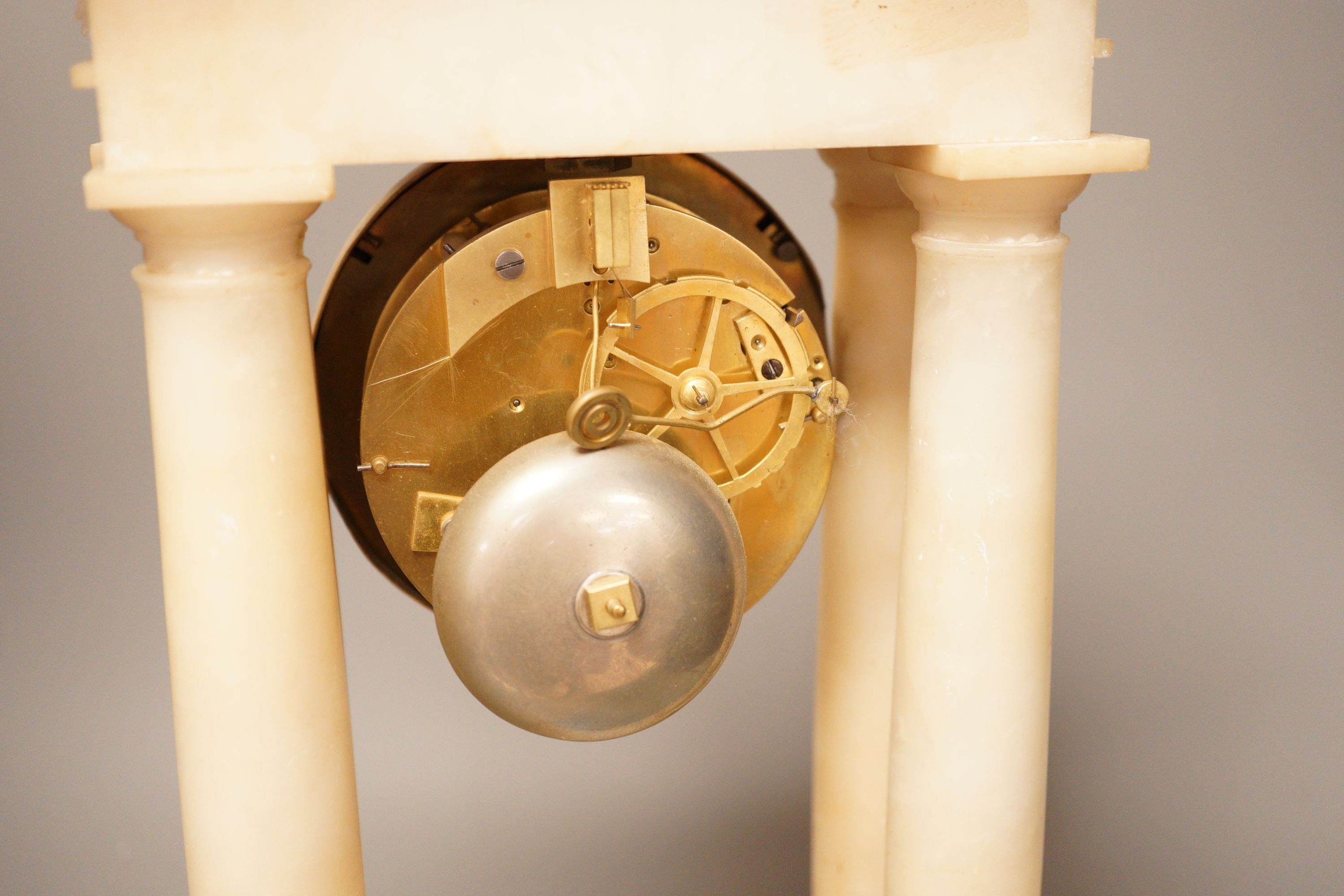 A 19th century alabaster portico clock with a gilt metal prowling lion decoration, 50cm tall